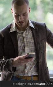Happy young businessman reading text message on smartphone