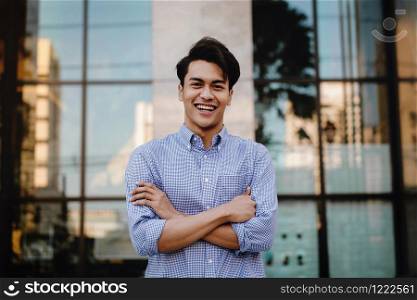 Happy Young Businessman Standing with a Big Smile in the City. Crossed Arms and Looking at Camera