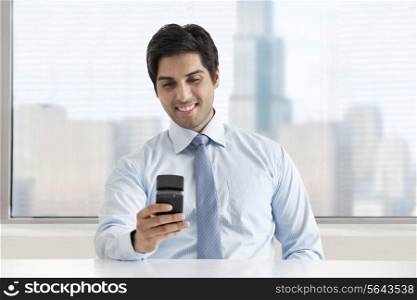 Happy young businessman texting message through cell phone