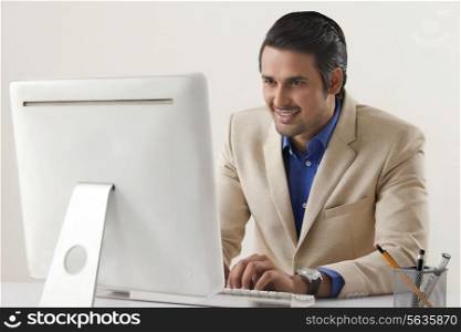 Happy young businessman using computer at office desk