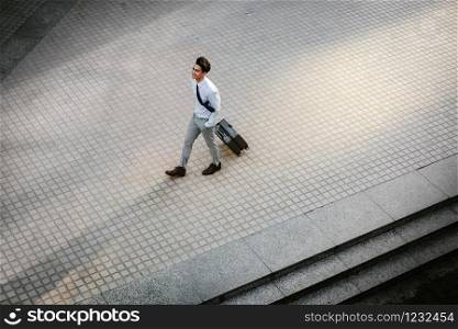 Happy Young Businessman Walking with Suitcase in the City. Modern Male in Business Trip. High Angle View. Full Length
