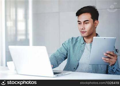 Happy Young Businessman Working on Computer Laptop and Digital Tablet in Office