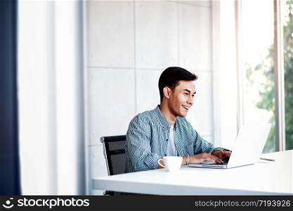 Happy Young Businessman Working on Computer Laptop in Office. Sitting on Desk, Man in Casual Wear