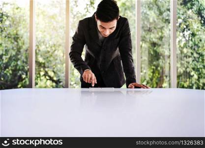 Happy Young Businessman Working on the Table in Office by Glass Window. Focus on Digital Tablet. Bottom View shot