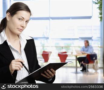 Happy young businesswoman holding open folder, smiling.