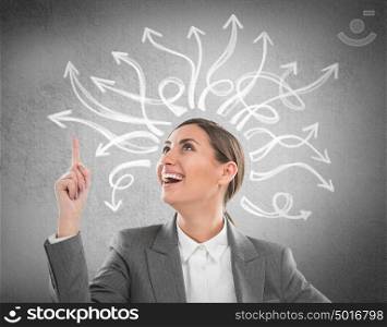 Happy, young businesswoman looking at many twisted arrows on the concrete wall overhead