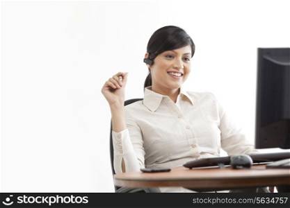 Happy young businesswoman on call while looking at computer