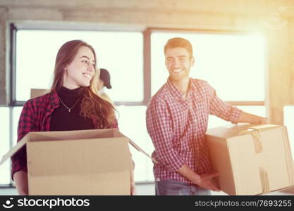 happy young casual business team carrying cardboard boxes with sunlight through the windows during moving in at new unfinished startup office building