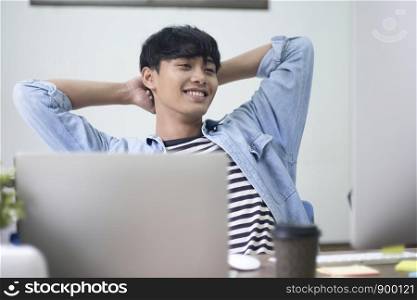 Happy young casual man relax resting while sitting at his working place in office.