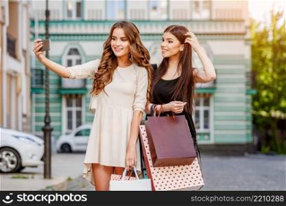 happy young caucasian women with shopping bags outdoor. happy young women with shopping bags