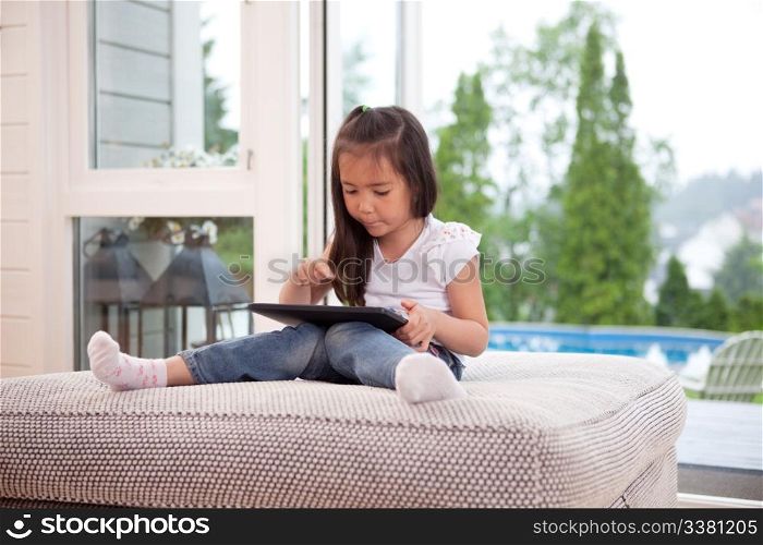 Happy young child playing with a digital tablet in an indoor setting