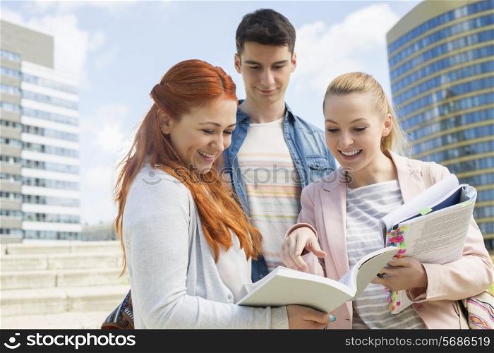 Happy young college students studying outdoors