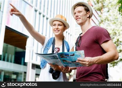 Happy young couple as tourists with a map. Look what we have there