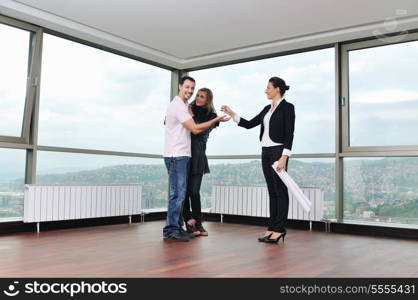 happy young couple buying new home with real estate agent and looking big comfort bright apartment plans and taking key