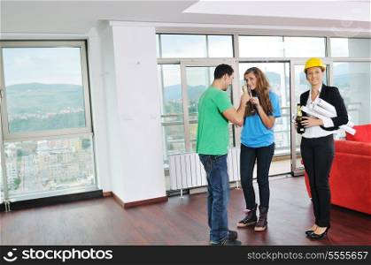 happy young couple buying new home with real estate agent and looking big comfort bright apartment plans and taking key