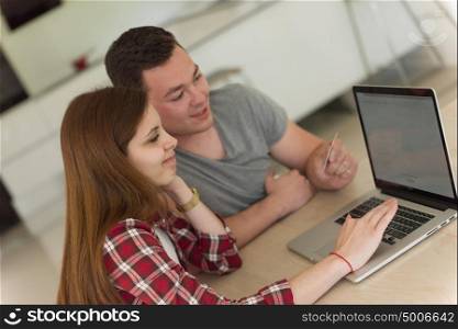 happy young couple buying online using laptop a computer and a credit card in their luxury home villa