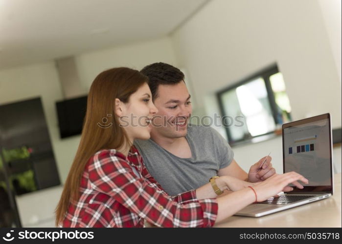 happy young couple buying online using laptop a computer and a credit card in their luxury home villa