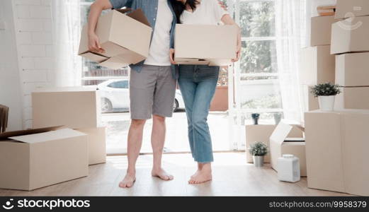 Happy young couple Carrying cardboard boxes and standing in the front door of a new house at moving day. Concept of relocation, rental, and homeowner moving at home.