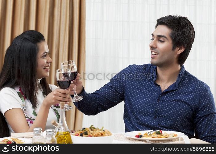 Happy young couple clinking wine glass during meal