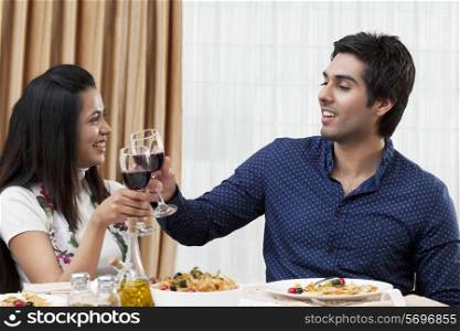 Happy young couple clinking wine glass during meal