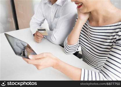 Happy young couple doing shopping online at home with tablet