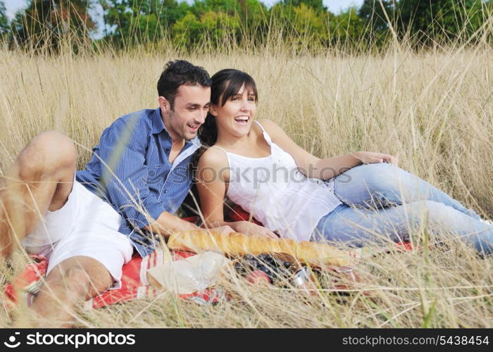 happy young couple enjoying picnic on the countryside in the field and have good time