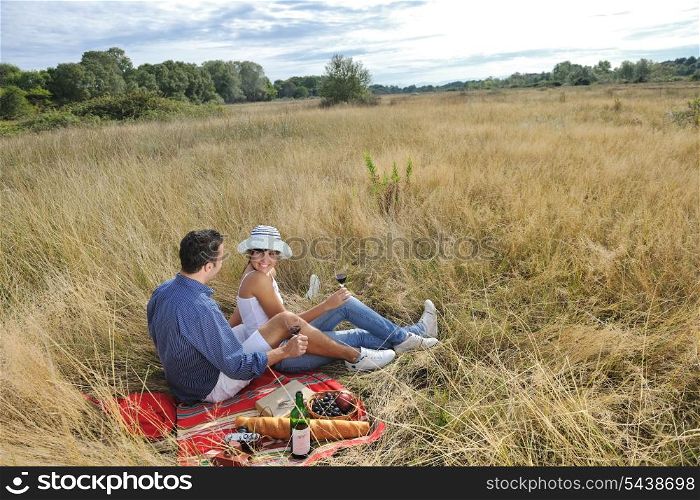 happy young couple enjoying picnic on the countryside in the field and have good time