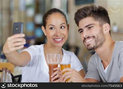 happy young couple enjoying some beers and taking a selfie