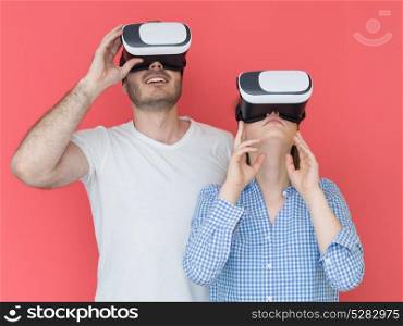 happy young couple getting experience using VR-headset glasses of virtual reality isolated over red background