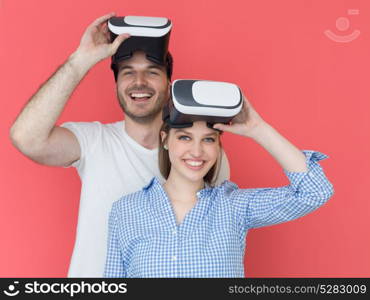 happy young couple getting experience using VR-headset glasses of virtual reality isolated over red background