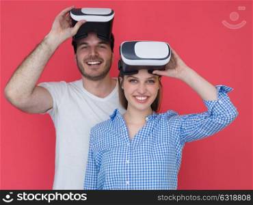 happy young couple getting experience using VR-headset glasses of virtual reality isolated over red background