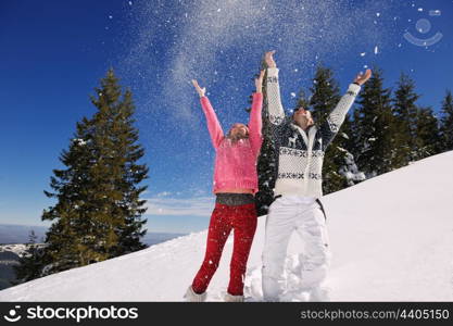 Happy young couple has fun on fresh snow at beautiful winter sunny day on vacation