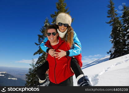 Happy young couple has fun on fresh snow at beautiful winter sunny day on vacation