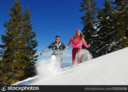 Happy young couple has fun on fresh snow at beautiful winter sunny day on vacation