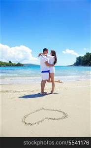 happy young couple have fun and relax on the summer with heart drawing on beach sand
