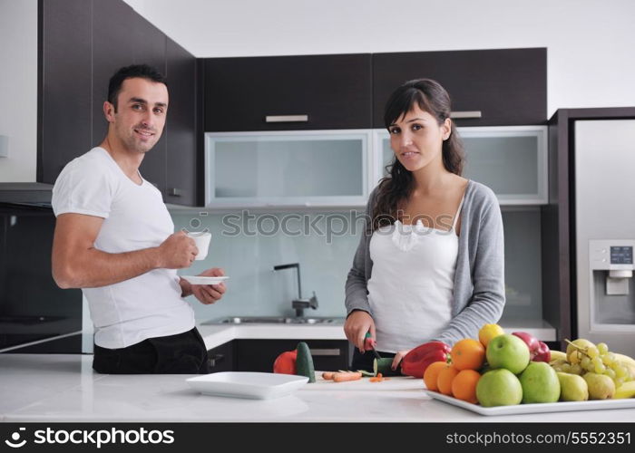 happy young couple have fun in modern kitchen indoor while preparing fresh fruits and vegetables food salad