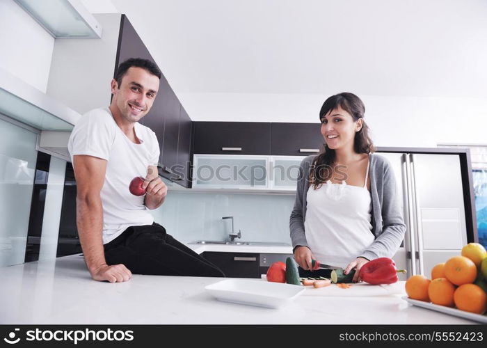 happy young couple have fun in modern kitchen indoor while preparing fresh fruits and vegetables food salad