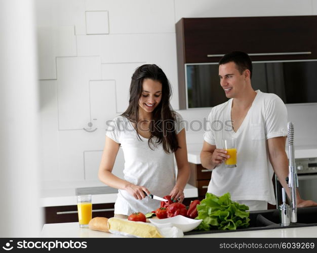 happy young couple have fun in modern kitchen indoor while preparing fresh fruits and vegetables food salad