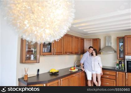 happy young couple have fun in modern wooden kitchen indoor while preparing fresh food