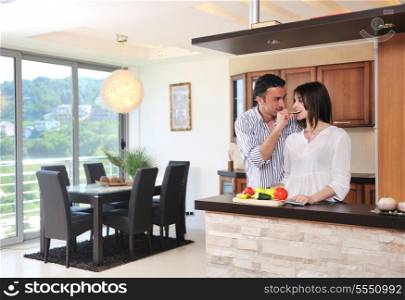 happy young couple have fun in modern wooden kitchen indoor while preparing fresh food