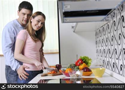 happy young couple have fun while preparing healthy fresh food in kitchen