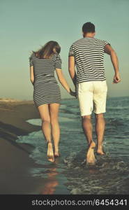 happy young couple have romantic time on beach at sunset