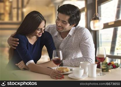Happy young couple having food at restaurant table