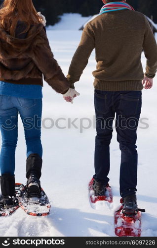 happy young couple having fun and walking in snow shoes. Romantic winter relaxation scene