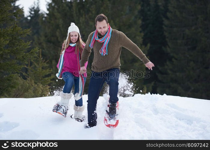 happy young couple having fun and walking in snow shoes. Romantic winter relaxation scene