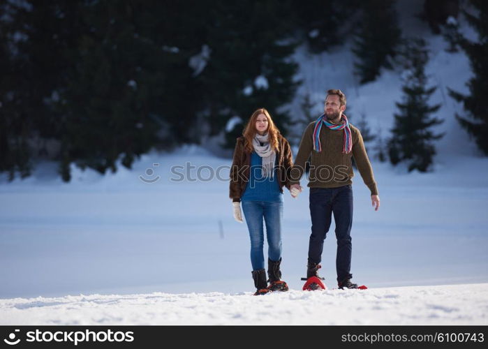 happy young couple having fun and walking in snow shoes. Romantic winter relaxation scene