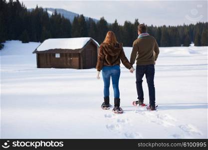 happy young couple having fun and walking in snow shoes. Romantic winter relaxation scene