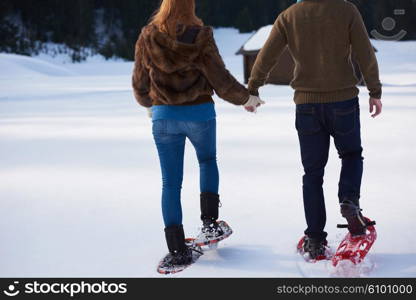 happy young couple having fun and walking in snow shoes. Romantic winter relaxation scene