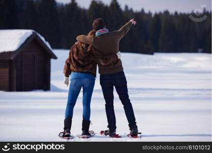 happy young couple having fun and walking in snow shoes. Romantic winter relaxation scene