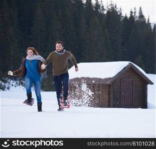 happy young couple having fun and walking in snow shoes. Romantic winter relaxation scene